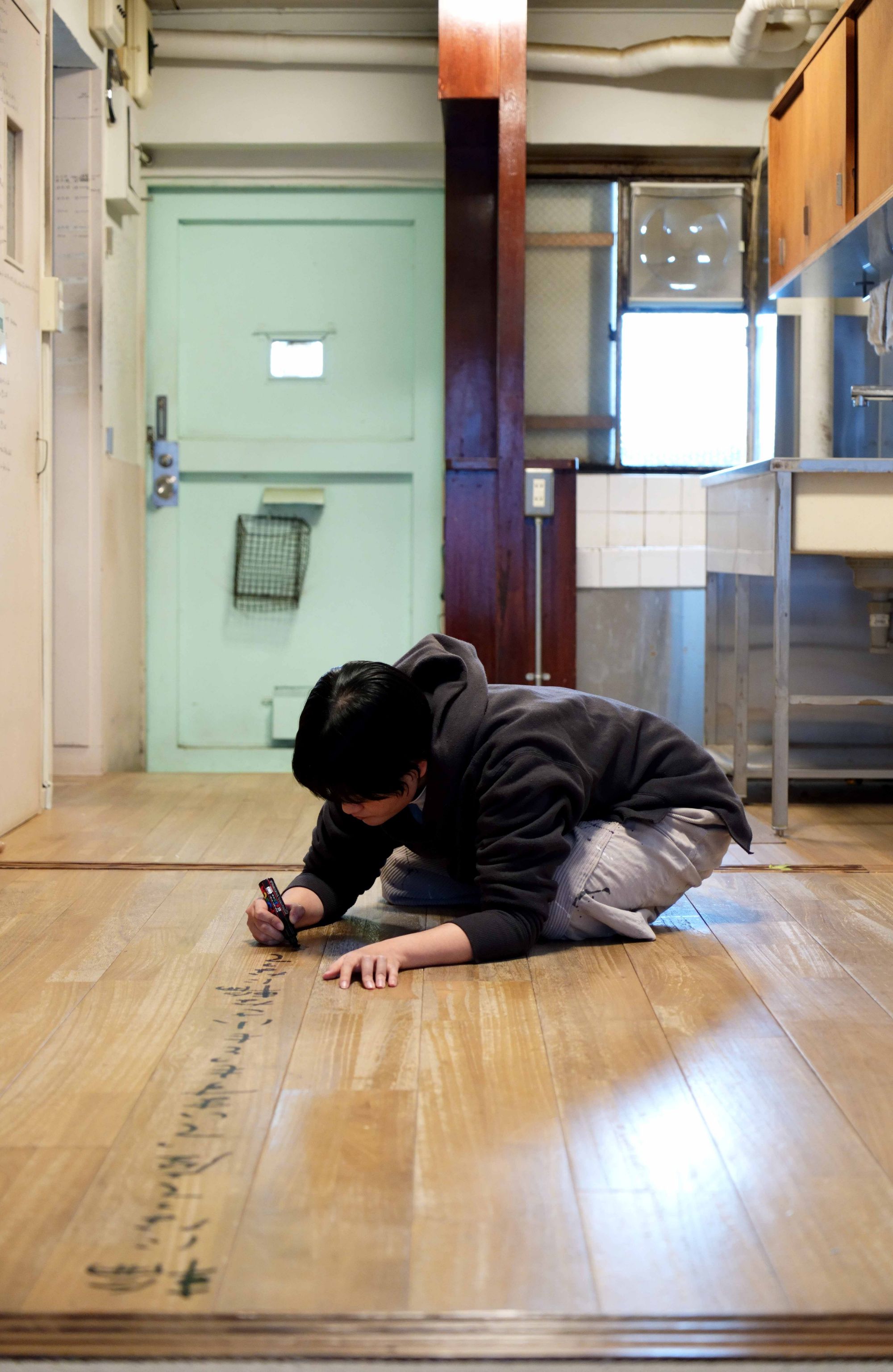 向坂くじら『アイムホーム』(百万年書房)書影から。床に詩を書き入れる向坂くじらの写真。撮影＝細川葉子