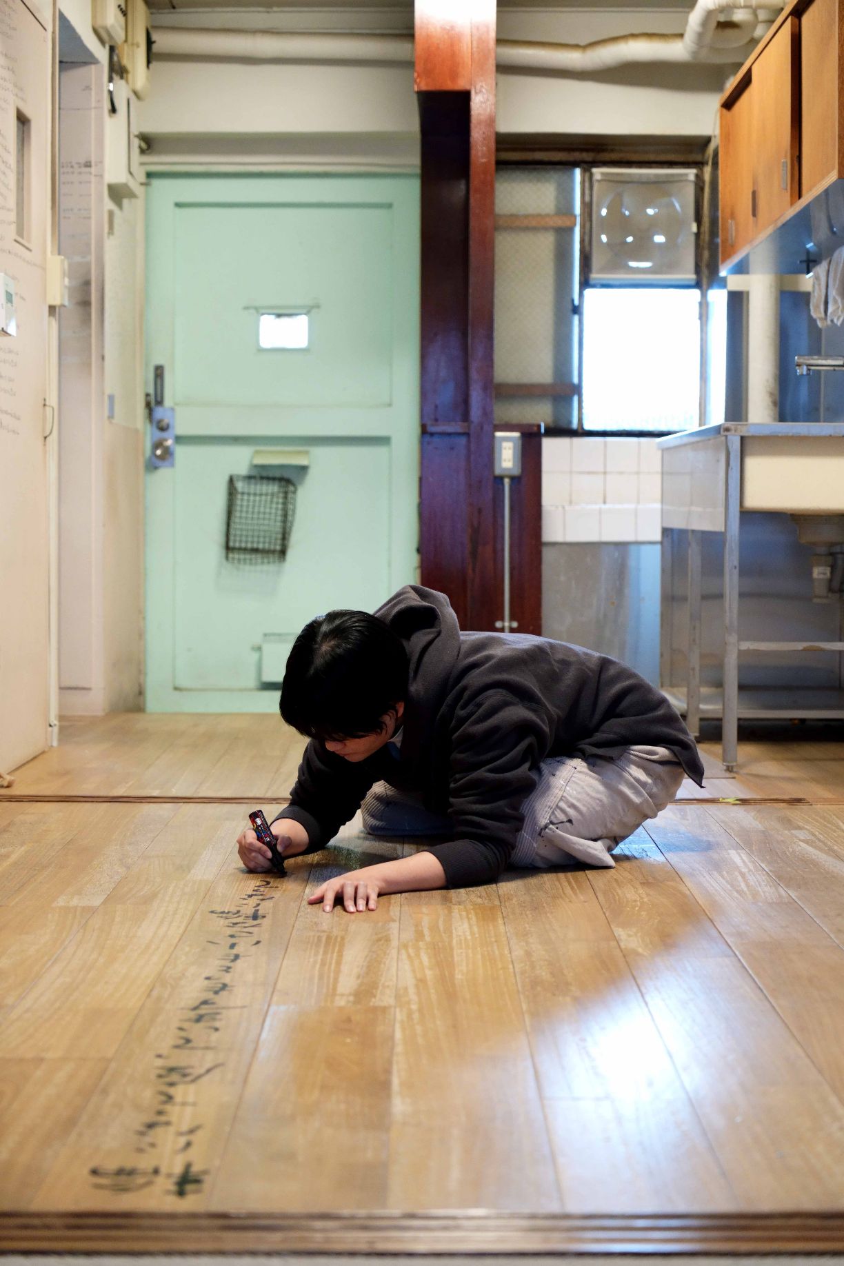 向坂くじら『アイムホーム』(百万年書房)書影から。床に詩を書き入れる向坂くじらの写真。撮影＝細川葉子